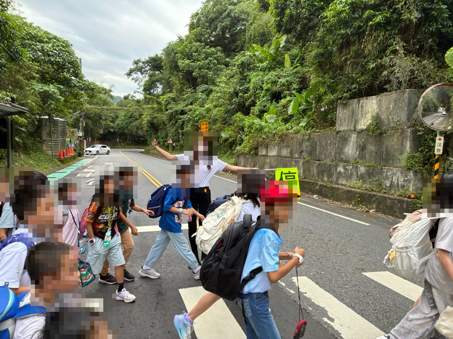 活動照片：導護家長志工站在馬路中央舉起停牌，孩子們走斑馬線過馬路