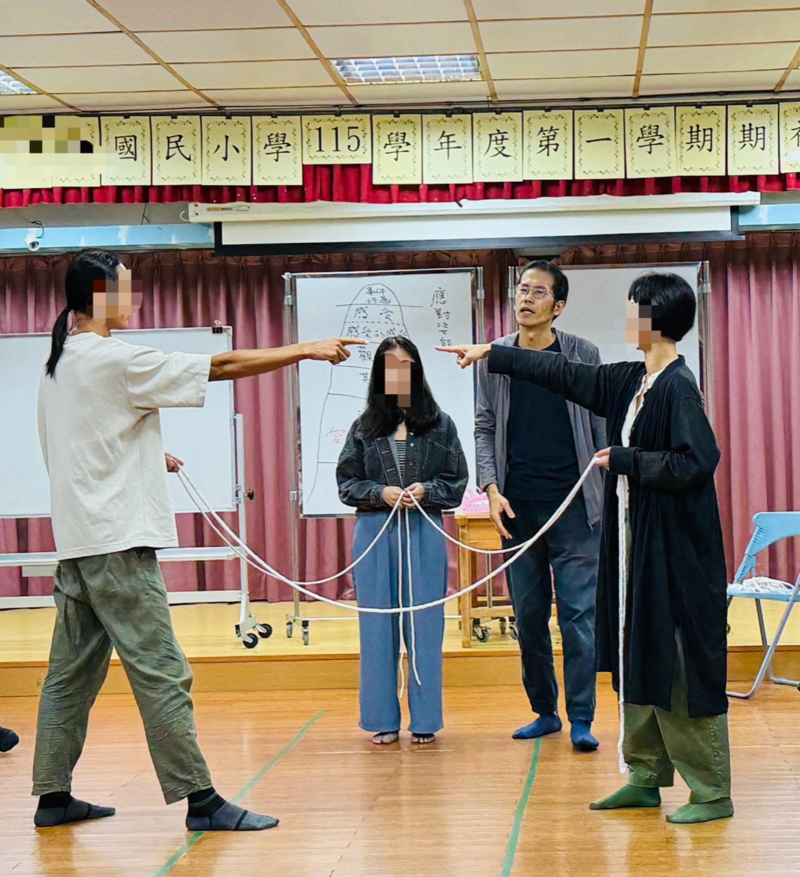 活動照片：四位學員在台上分別扮演爸爸、媽媽與兩個孩子，彼此以童軍繩相連，講師在旁說明